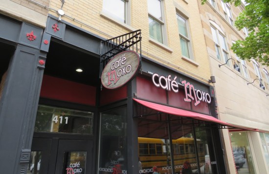 Worms's-eye-view shot of Cafe Moxo. The M in the logo and the awning are fuchsia.