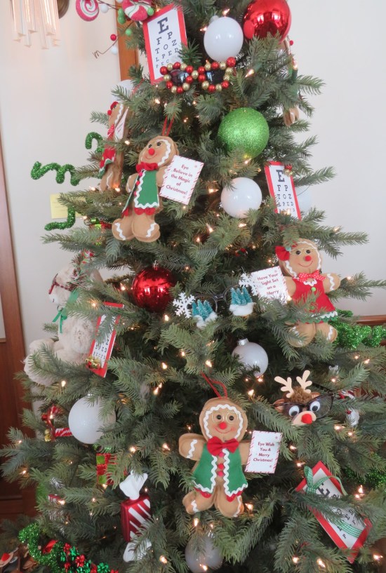 Christmas tree decorated with eye exam charts, gingerbread people, white balls.