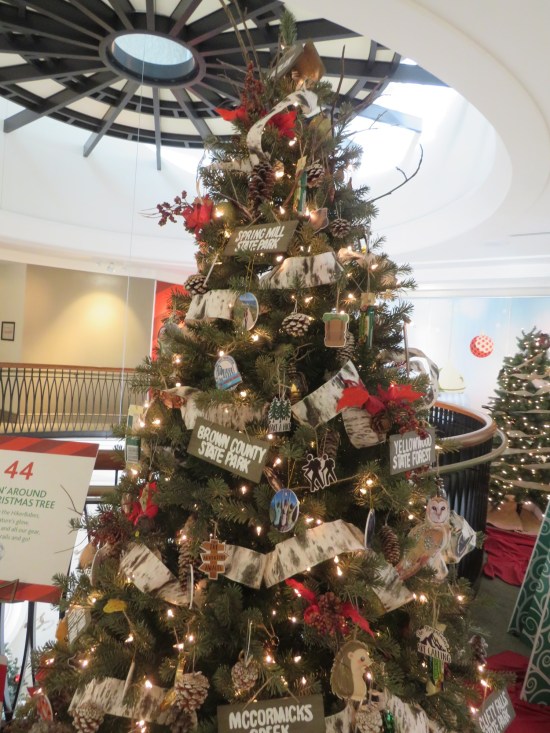 Christmas tree decorated with woodsy evergreen elements and signs for Indiana parks including Brown County, Spring Mill, and McCormick's Creek.