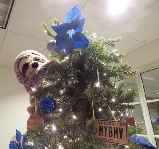 Christmas treetop with stuffed sloth and little IN BMV license plates.