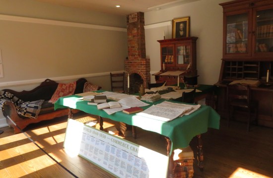 Law office furniture roped off: couch, two desks, fireplace, and table covered in books and papers.