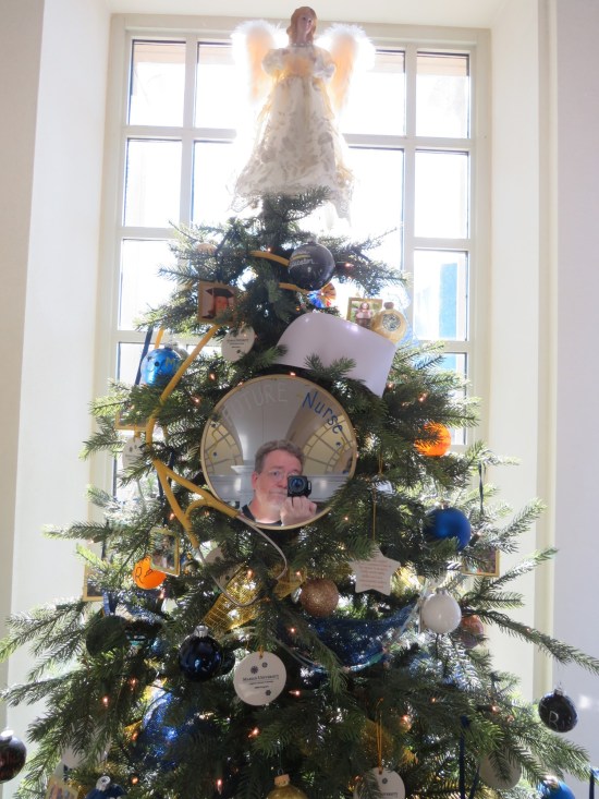 Christmas tree decorated with an angel topper and a mirror with "FUTURE NURSE| written across the top. My camera and face are reflected in it.