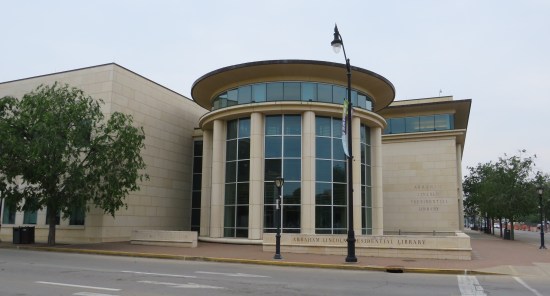 Rotunda exterior, six columns divided by paned windows top to bottom. Library name carved on the outside at the side and on a concrete bench in front.
