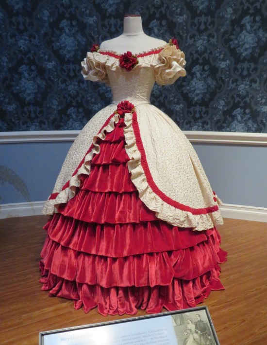 Red and white dress with a large rose on each shoulder, on the chest and in the belt-buckle area.