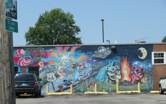 A mural of hippie teddy bears driving a van, singing around a campfire, and hitchhiking. Other details include a UFO, a floating skull radiating groovy vibes, and Disney's Cheshire Cat.