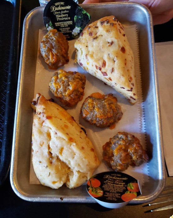 Metal tray with two scones, four meatballs, and two packets of jelly.