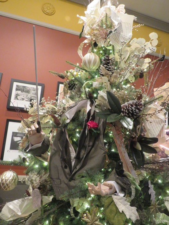 Christmas tree decorated with conductor's jacket, wand, and mannequin hands posed just so.