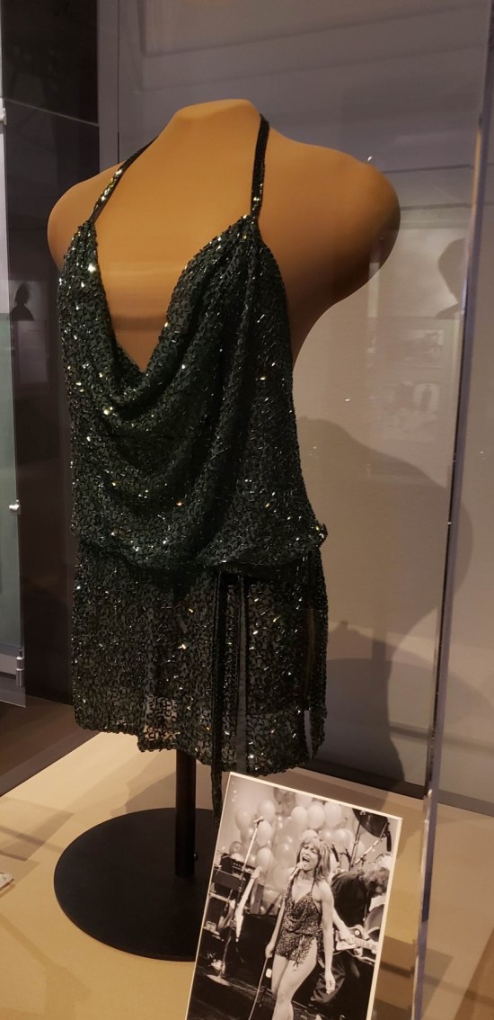Glittery skimpy black dress with very thin shoulder straps and plunging neckline.