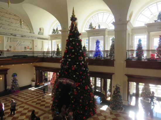 museum lobby with 30-foot Christmas tree in the middle and other normal-sized Christmas trees in every alcove and along every wall.