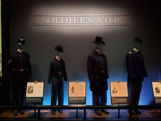 Four different Civil War uniforms on the Union side, lined up under a display titled A Soldier's Story".