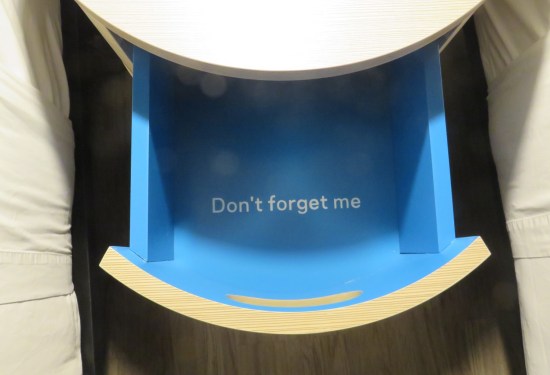 White nightstand with yellow-paneled drawer with blue interior. Written on the bottom of the drawer is DON'T FORGET ME.