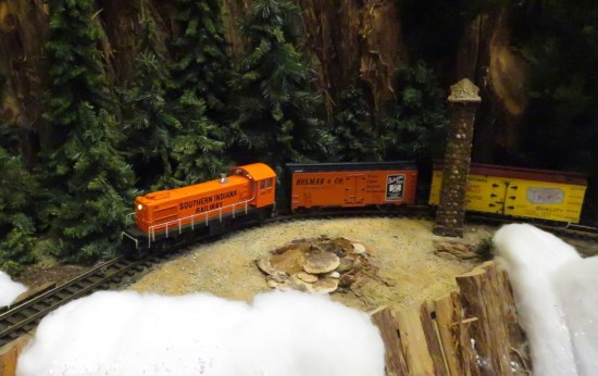 toy train runs past tiny model of Old Faithful.