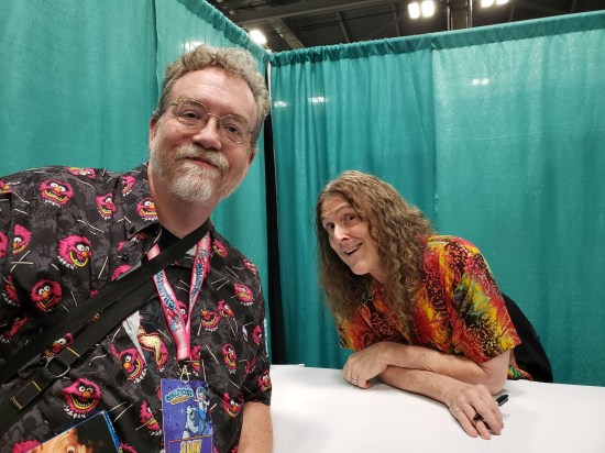 Me looming over a smiling, seated Weird Al. Turquoise curtains surround us on all sides.