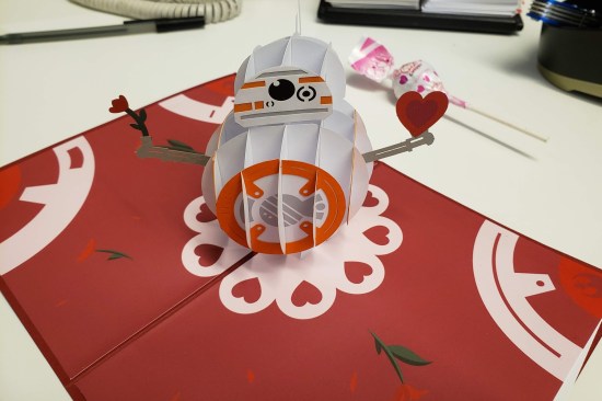 Valentine's Day card with a lovely 3-dimensional pop-up paper BB-8 droid. The card is red with white holiday trimmings in the corners.
