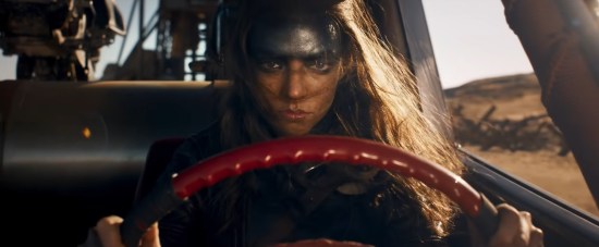 Young Furiosa angrily driving with a red steering wheel.