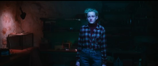 Woman with pricey hairdo and flannel shirt in a dark room viewed through a werewolf's perspective so the colors are weirdly red and blue around the shadows.