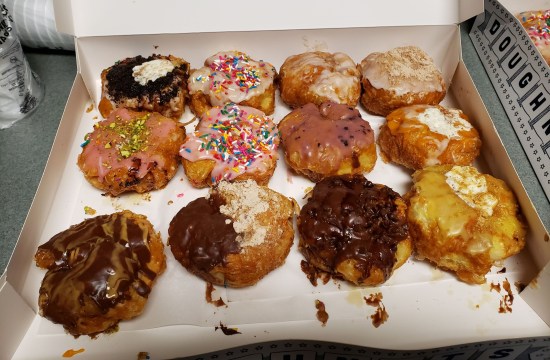 A dozen sinfully giant donuts in mostly different icings and flavors.