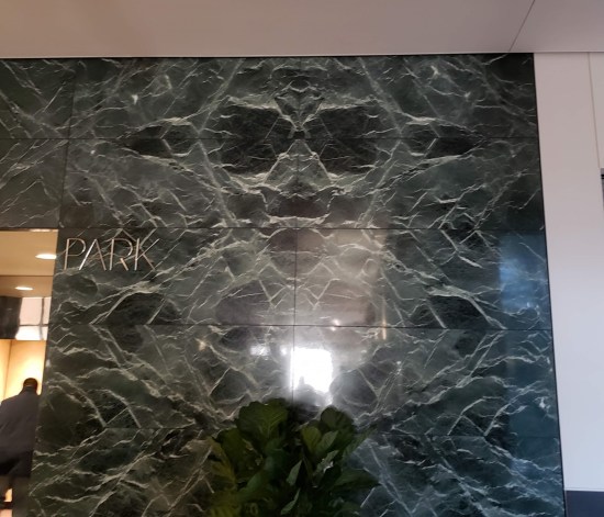 Greenish marble wall with off-white random lines throughout. At the top, the lines appear to form a head with large eye sockets and flat, pointed ears sticking out.