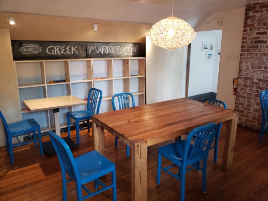 Attic with square wall shelves, wooden table and blue plastic lawn chairs.