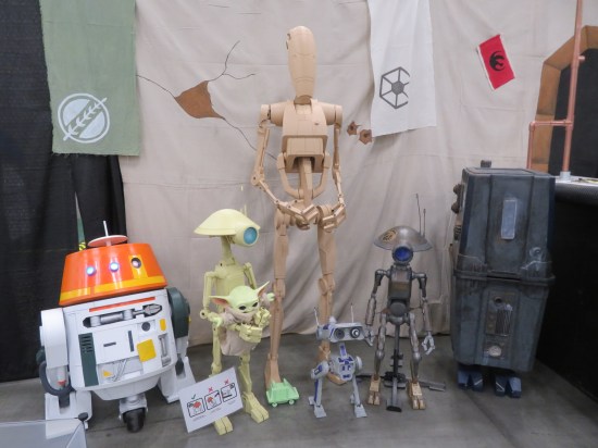 Replicas of R5-D4, two Pit Droids (one holding a Grogu doll), a Battle Droid, a Gonk Droid, and a tiny one from the sequel trilogy whose name escapes me.