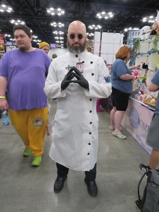 cosplay: Hugo Strange in Arkham Asylum scientist coat, fingertips touching evilly.