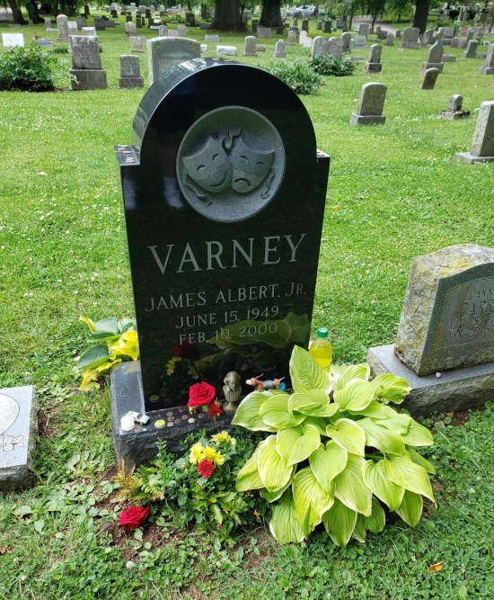 Jim Varney's tombstone with a large green plant, small Slinky Dog and other items left in tribute.