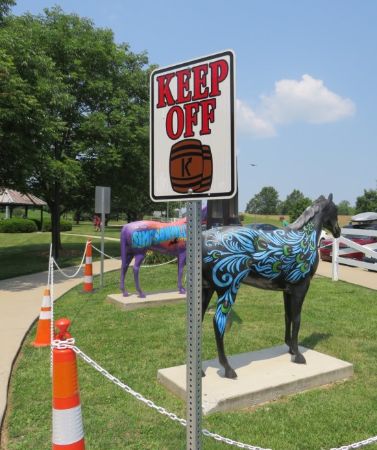 "Keep Off" sign in the horse statue enclosure, with tiny liquor barrels drawn under the word "OFF".