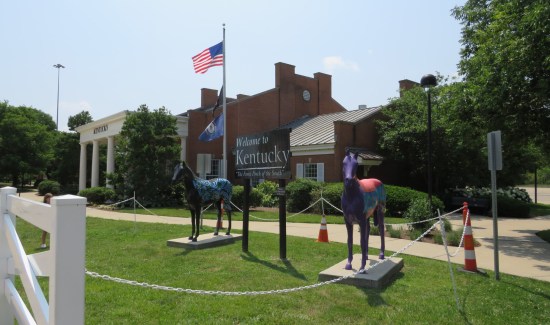 Kentucky welcome center with lots of greenery and two horse statues out front.