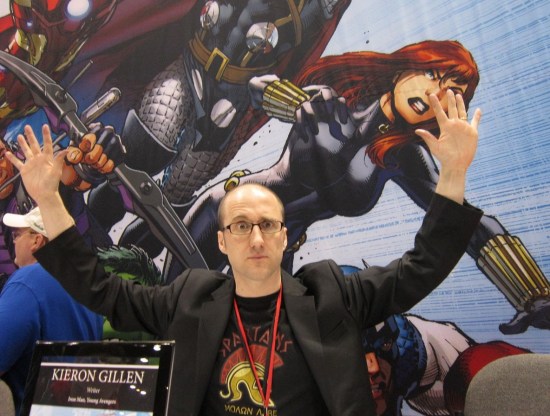 A young Kieron Gillen seated at a Marvel signing both, arms spread wide as if entertaining the masses in a coliseum.