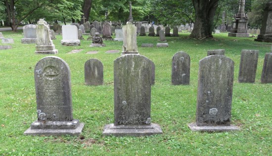 Three tombstones in a row, severely eroded but the one at right definitely says Harriet C. McCullough.