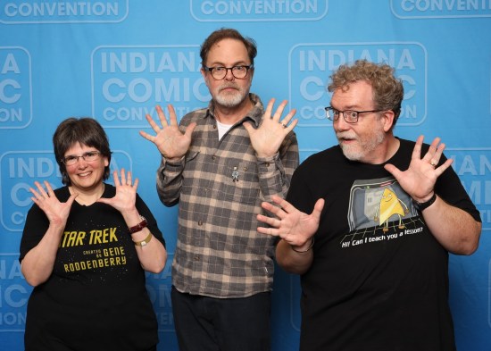 Us doing jazz hands with Rainn Wilson, who wears a flannel shirt, glasses, beard, and glum Dwight-like expression.