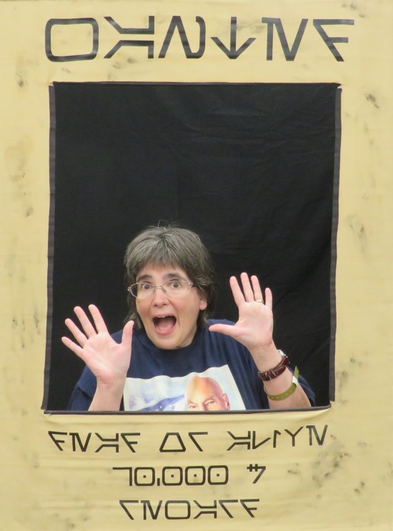 Anne doing jazz hands inside a "wanted" poster frame written in the Star Wars Aurebesh fake language code.