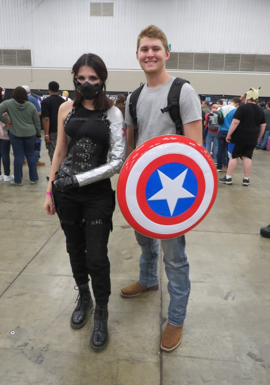 cosplay: Winter Soldier with mask and gun, and Steve Rogers in grauy T-shirt with shield.