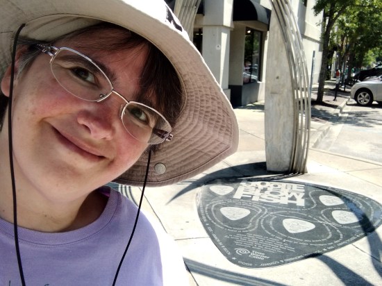 Anne selfie with Hootie guitar-pick plaque on the ground.