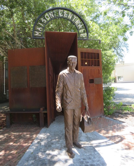 Sculpture of a relaxed military man exiting a hallway, carrying a travel bag.