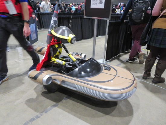 Tiny Landspeeder with a Pit Droid sitting in it, parked at the end of an autograph line.