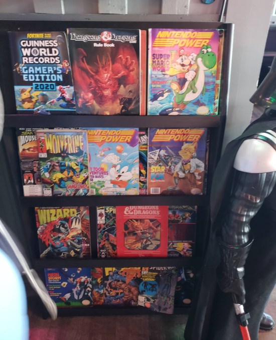 magazine rack filled with Wizard Magazine, Nintendo Power, a few 1990s Marvel comics, D&D stuff and more.
