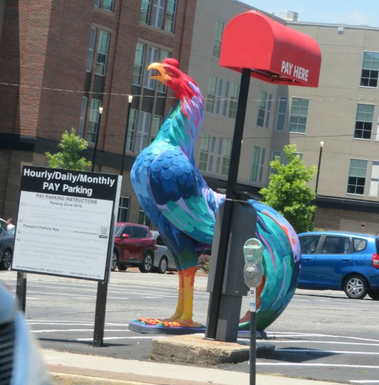rooster statue standing in a mostly empty parking lot.