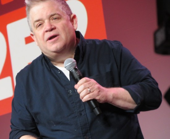 Dutch-angle shot of Oswalt on stage, unintentionally cutting off the top of his head.