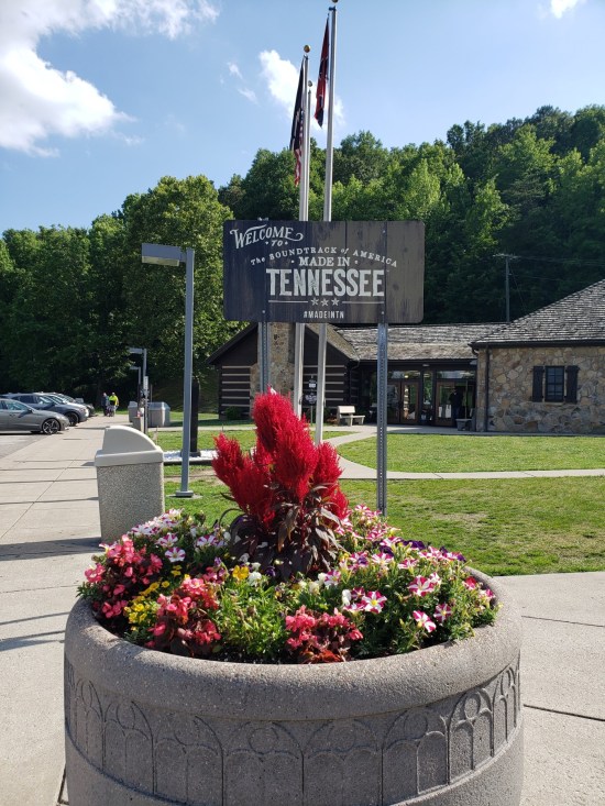 Tennessee welcome center with sign in the foreground and a large flower planter.