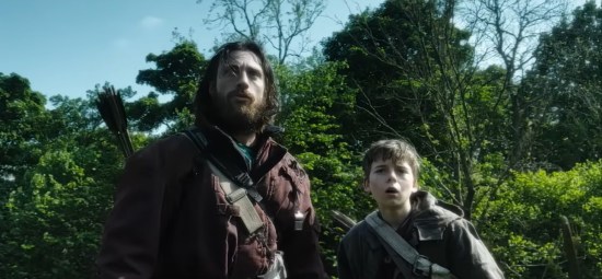 Aaron Taylor-Johnson and a kid actor each dressed like Robin Hood with no hoods, looking incredulously at something offscreen.