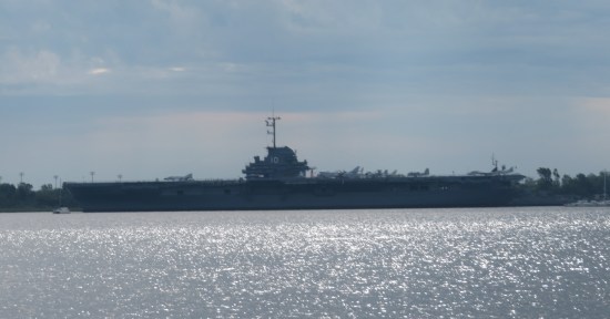 Distant aircraft carrier next to a museum, which is on the other side and obscured.