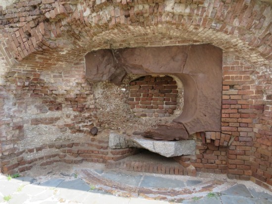 Brick wall with protuberances that used to be added features, now crumbling.