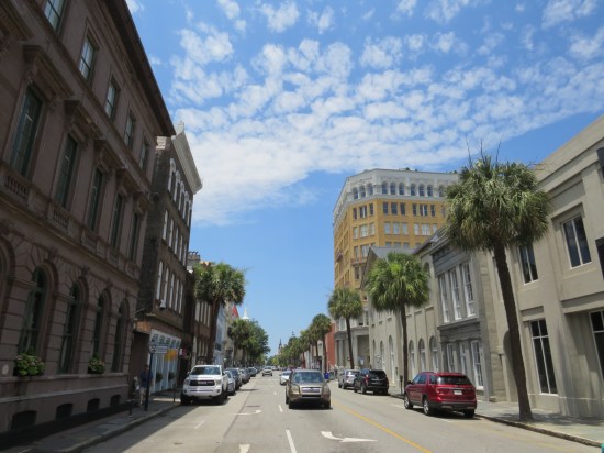 City street lined with old yet maintained buildings and a few palmettos.