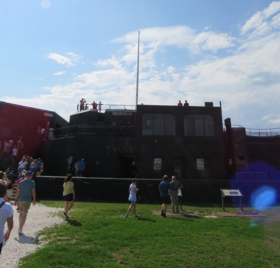Two-story black building inside a fort with empty flagpole.