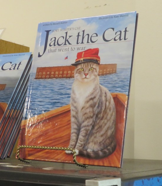Actual children's book on a gift shop shelf. Cover is a gray tabby at Fort Sumter wearing a red cap.