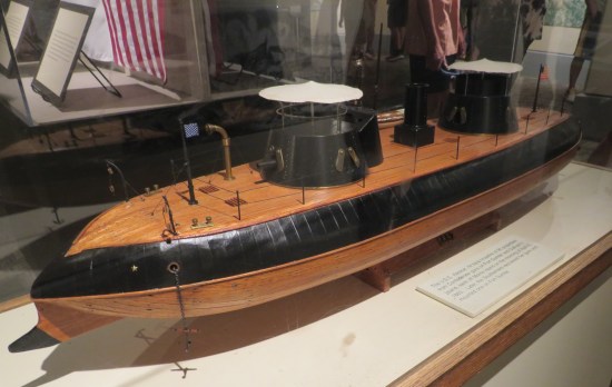 Large model of wooden warship with black features that I thought was a submarine at first because of the hull's tapered aerodynamic design.