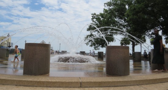 Much flatter fountain, short enough to climb on, with waterspouts around the perimeter firing water arches toward the center.