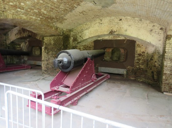 cannon pointed at a wall where there used to be a hole to shoot through, now sealed with more bricks.