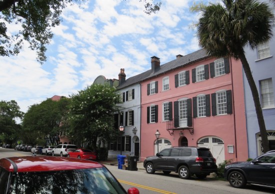 rainbow row houses in pink and blue, trees blocking the houses on the left.